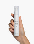 Hand holding VIBRANT® RESTORE Barrier Repair Moisturizer on white background