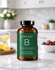 Supplement bottle labeled 'Vibrant B' on a kitchen counter with lemons and berries in the background.