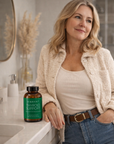 Woman holding a bottle of 'Immune Support' supplements in a bathroom.