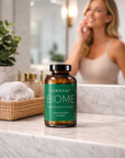 Bottle of Vibrant Biome supplement on a bathroom counter with a woman in the background.