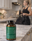 Vibrant Adrenal Support supplement bottle on a kitchen counter with a blurred person in the background.