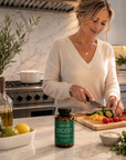 Woman preparing food in a kitchen with a bottle of Vibrant Digest on the counter.