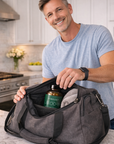 Man holding a gray duffel bag with a bottle of 'Vibrant Libido' in a kitchen.