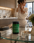 Woman adjusting earrings in a modern kitchen with a Vibrant supplement container on the counter.