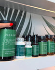 Hand holding a 'Vibrant' supplement bottle with various other supplements on a shelf.