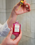 Hand holding VIBRANT® DESERT VIBE Barrier Hydration Serum in a luxury bathroom setting