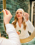 Woman applying Vibrant Neuro Vibe Superfood Oil serum while looking in mirror