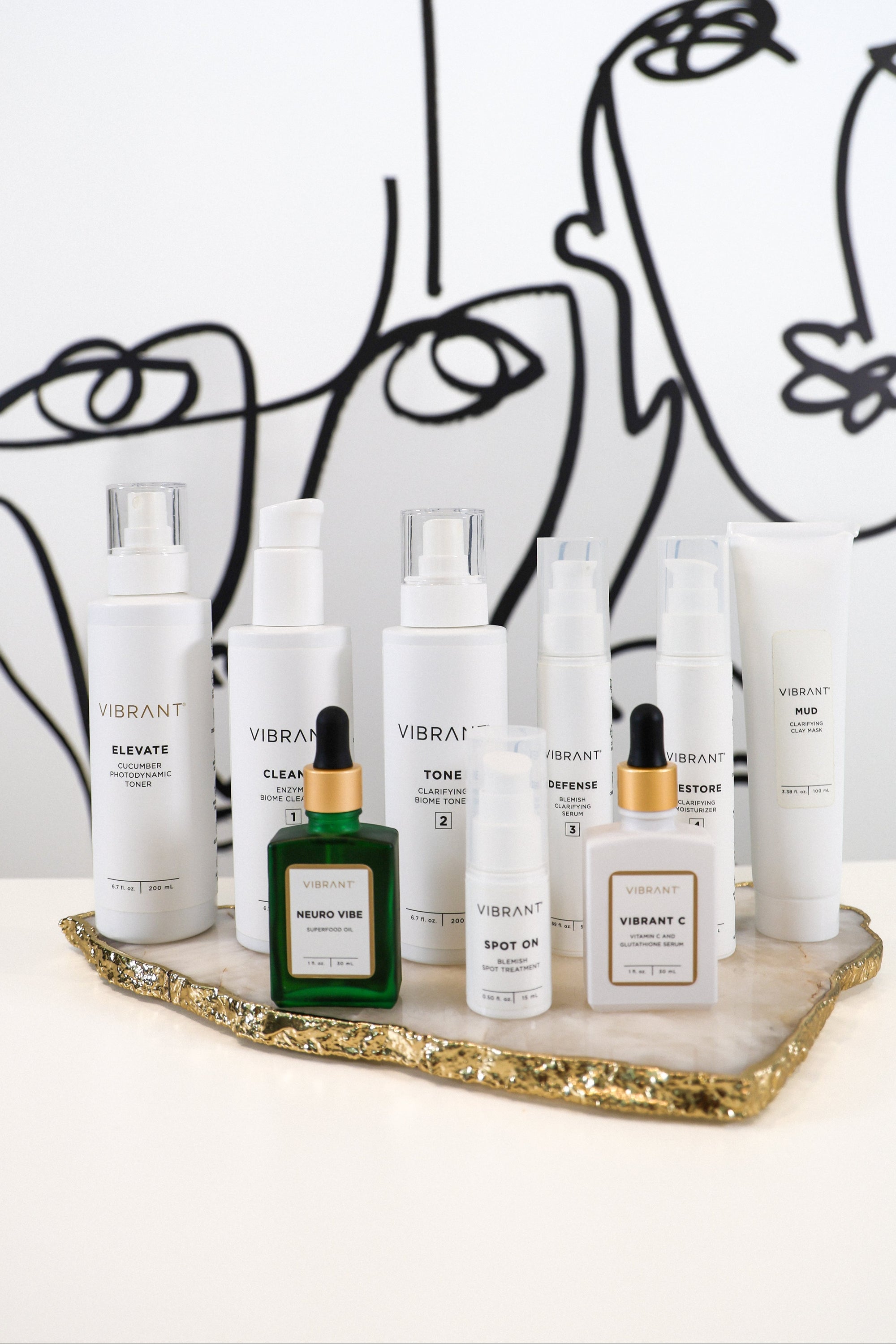 Collection of skincare products on a marble tray with abstract line art in the background