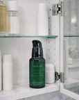 Green bottle labeled 'Vibrant' on a shelf with other skincare products in a bathroom setting.
