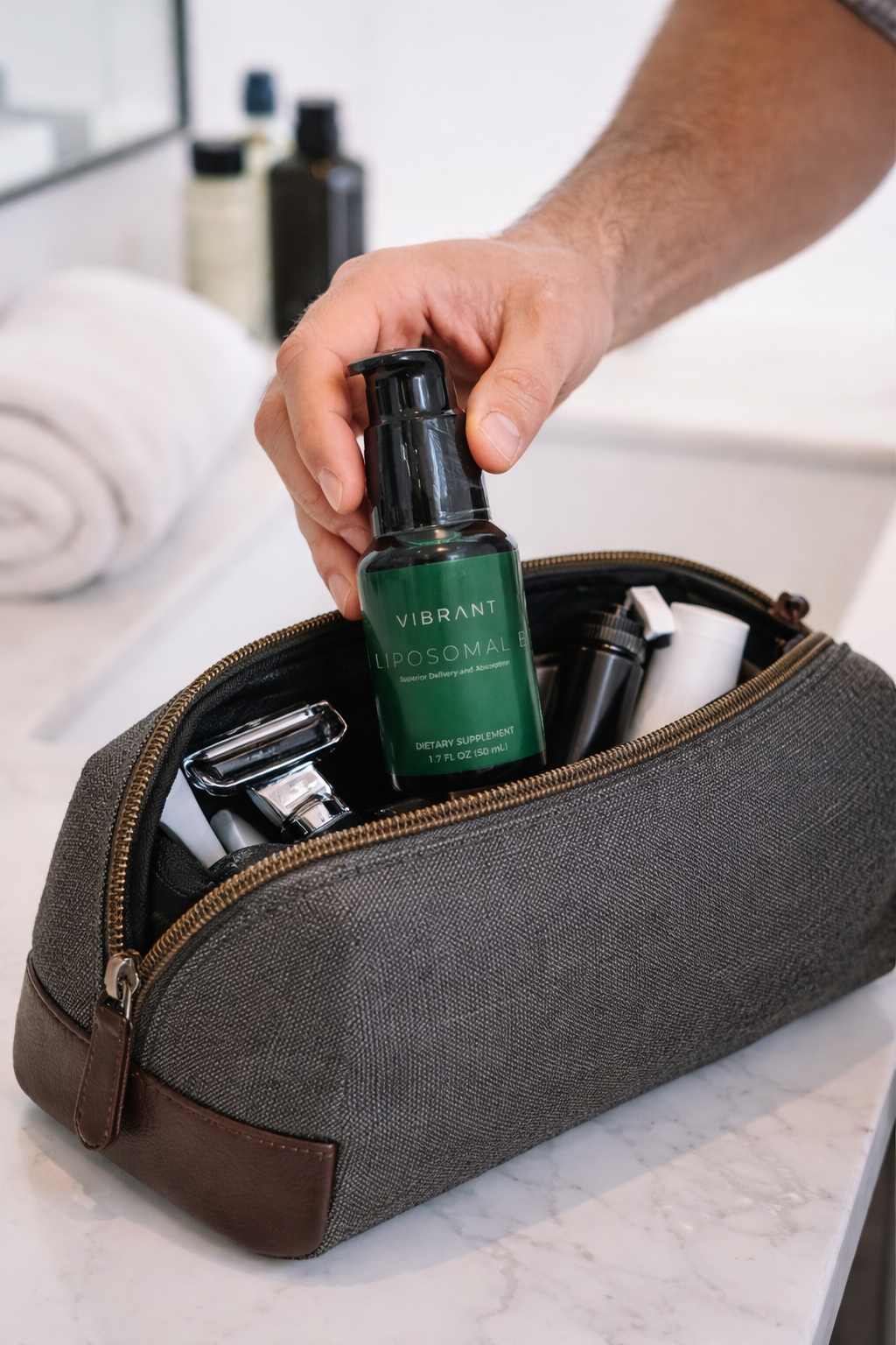 Person reaching into a gray toiletry bag with grooming products on a marble surface.