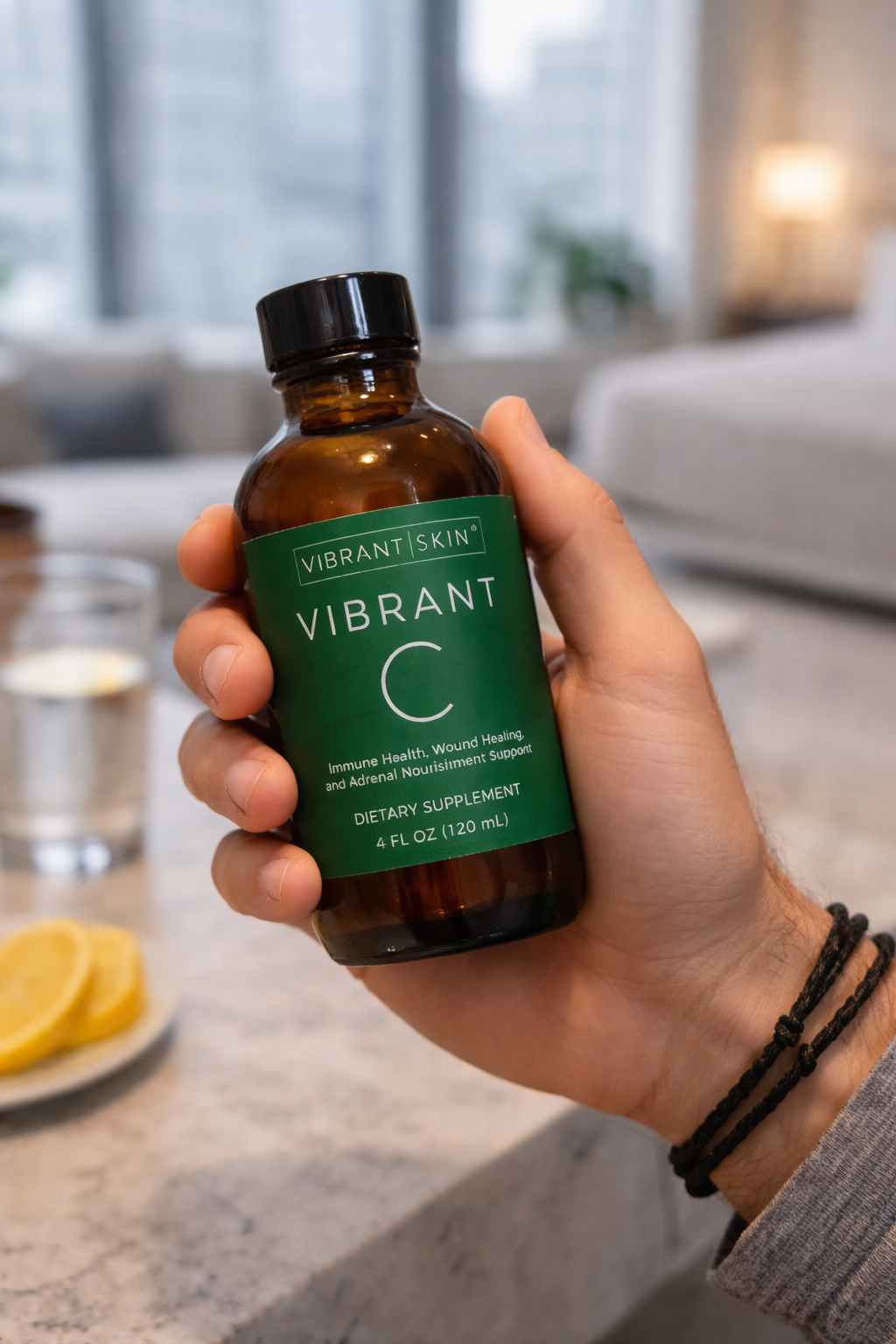 Hand holding a bottle of 'Vibrant Skin Vibrant C' dietary supplement in a kitchen setting.