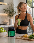 Woman holding a green smoothie in a kitchen with a Vibrant Collagen container.