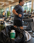Middle-aged man working out in a modern gym with a Vibrant Crave Control bottle visible inside an open gym bag in the foreground.