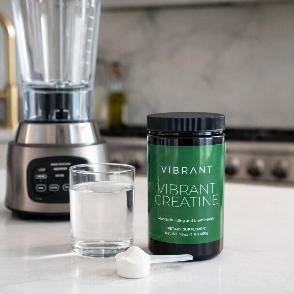 Vibrant Creatine supplement container on a kitchen counter with a blender and glass of liquid in the background.