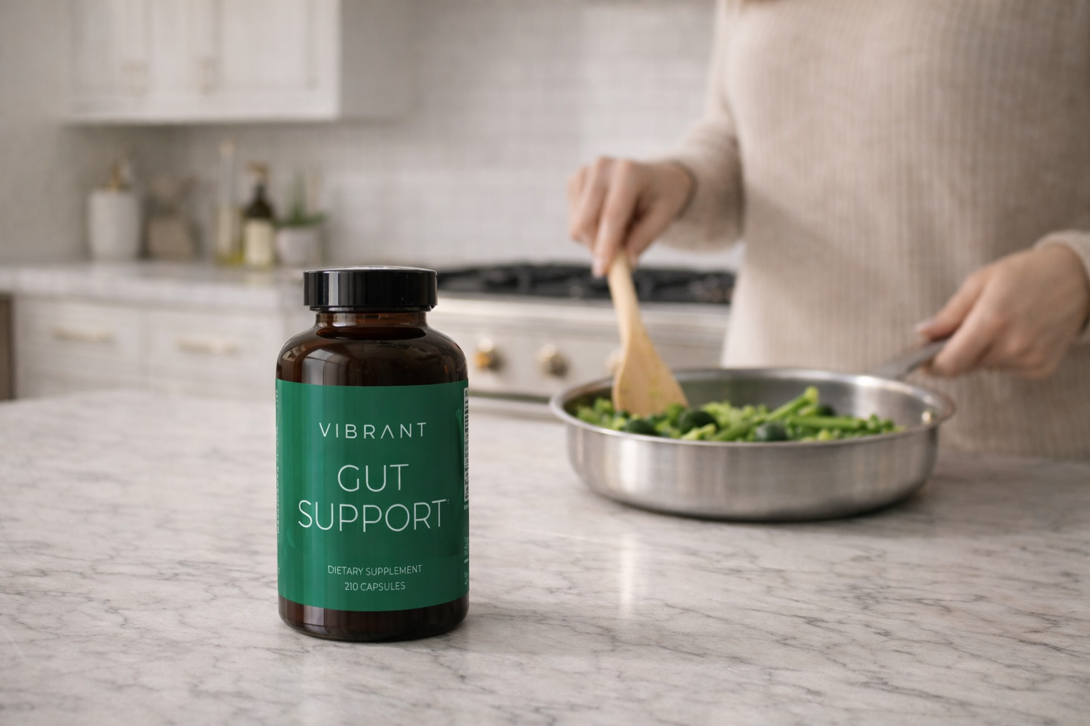 Bottle of 'Vibrant Gut Support' on a kitchen counter with a person cooking.