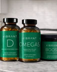 Three supplement containers labeled 'Vibrant D', 'Vibrant Omegas', and 'Vibrant Boost' on a kitchen counter.