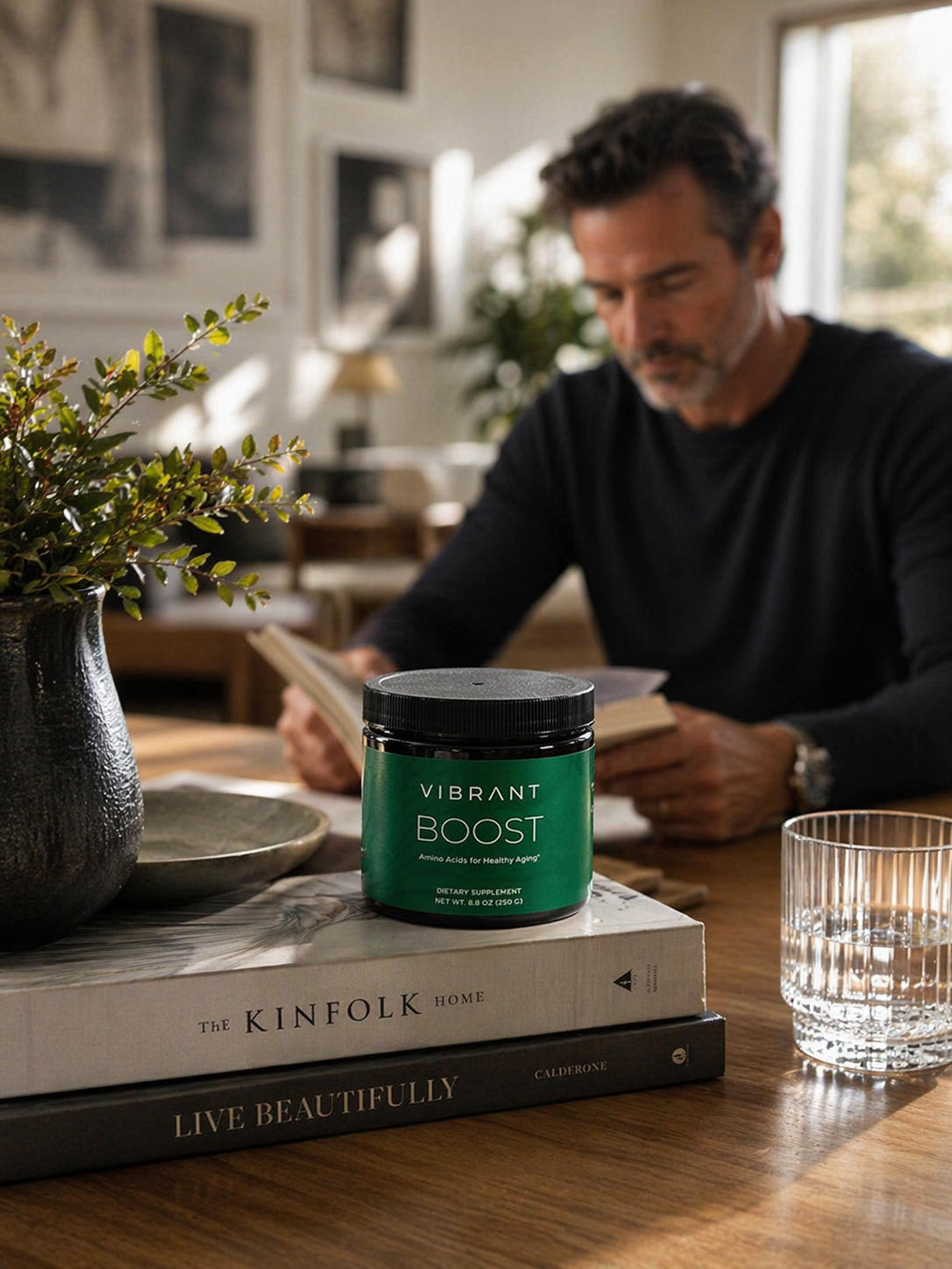 Man reading a book with a 'Vibrant Boost' container on a table