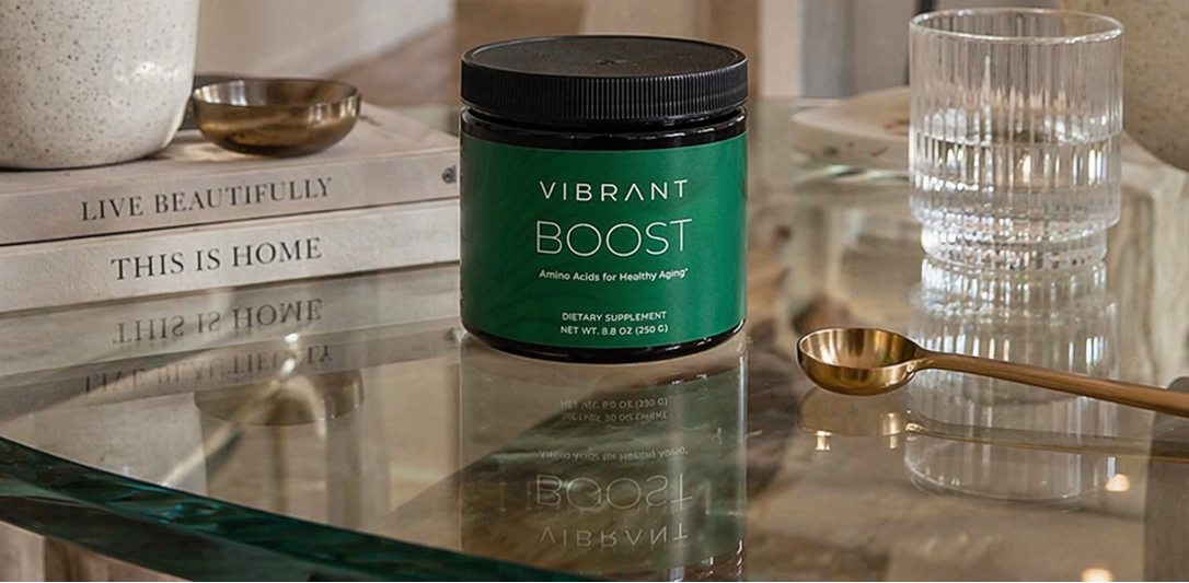 Woman in a kitchen with a jar of 'Vibrant Boost' on a table.