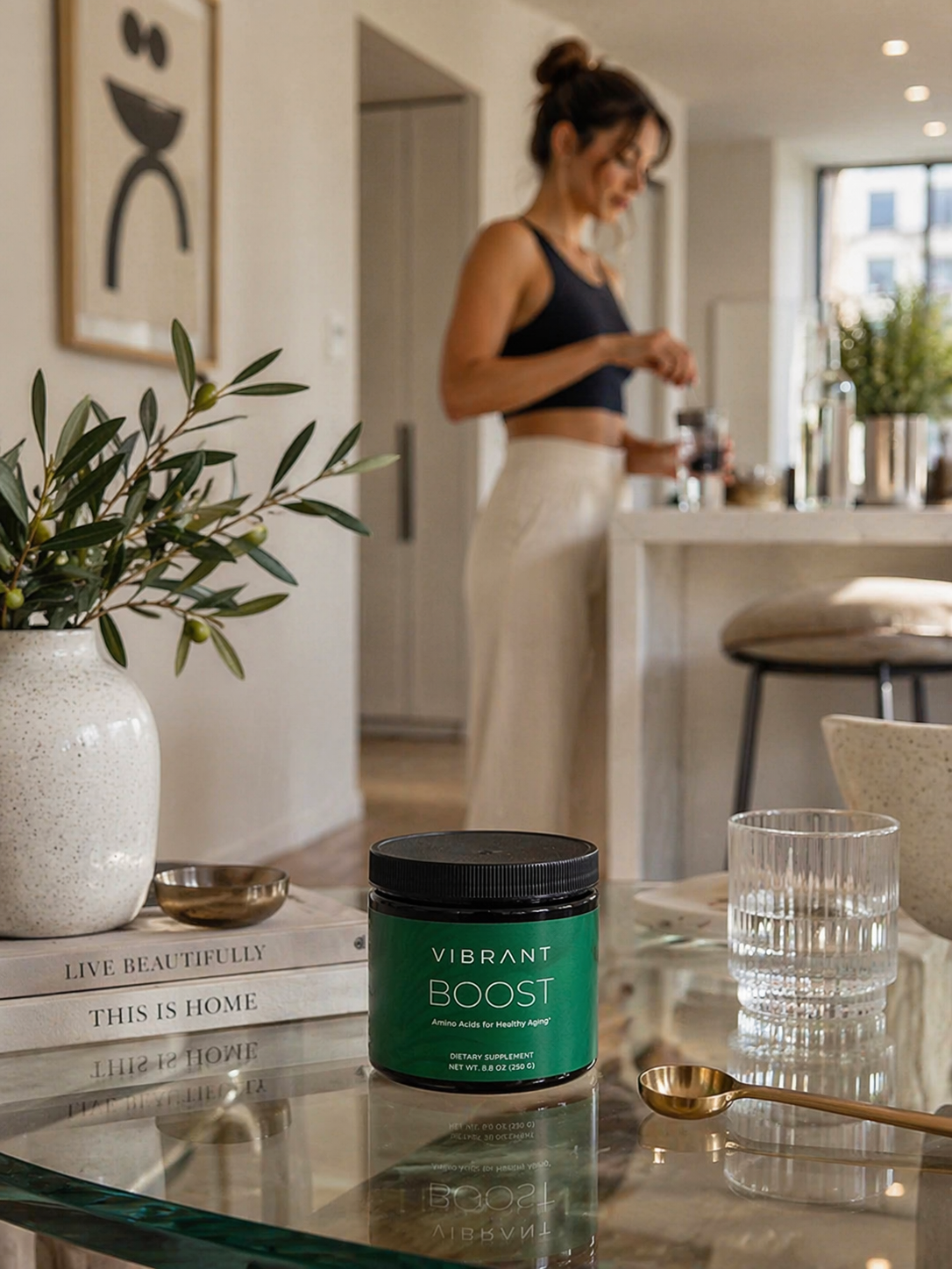 Woman in a kitchen with a jar of 'Vibrant Boost' on a table.